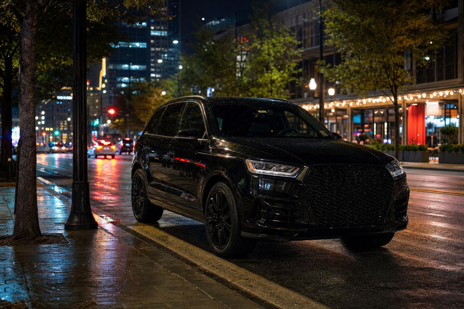 A black luxury SUV on a downtown Atlanta street at night with glowing city lights